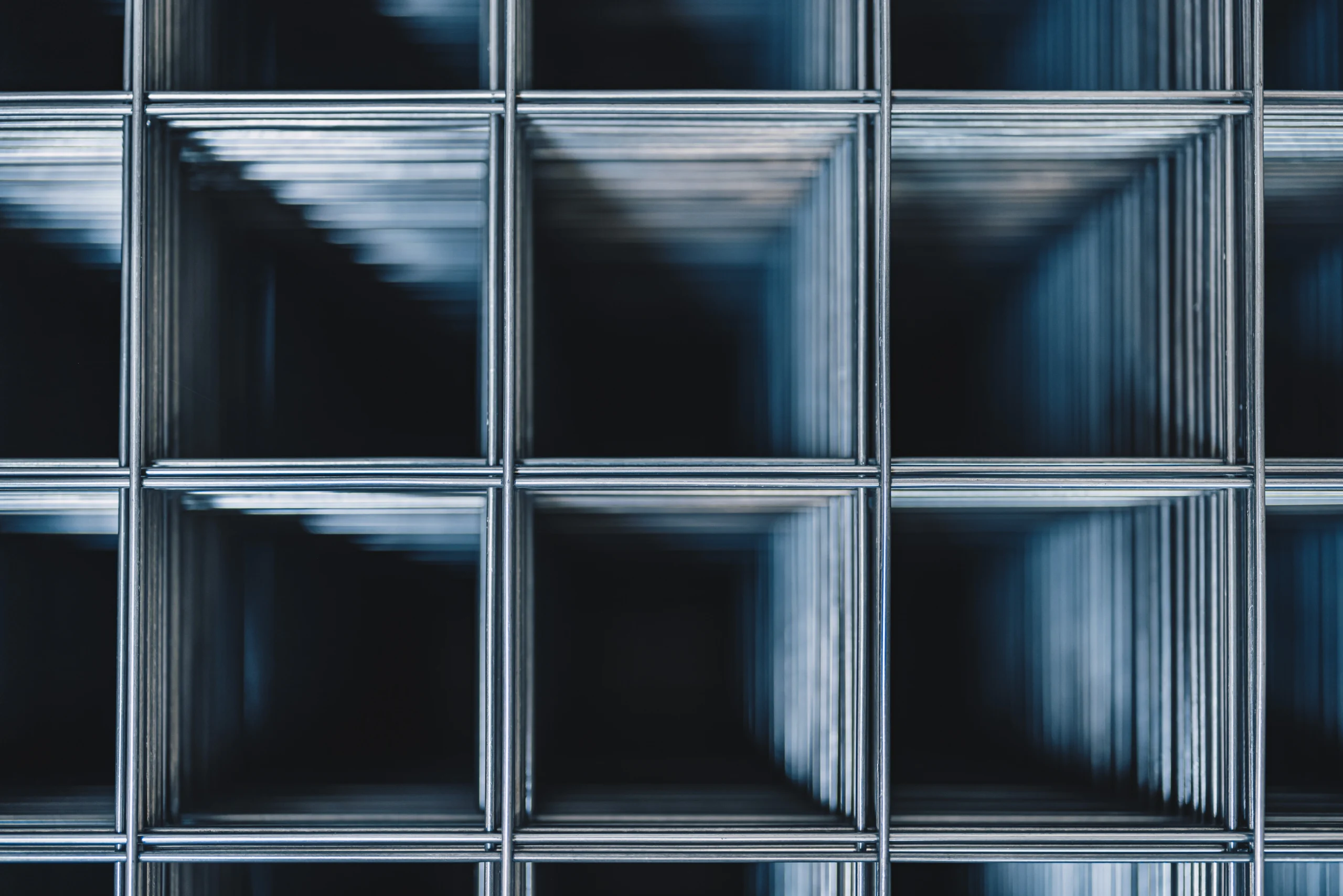 Frontale Nahaufnahme gestapelter Heizungsgittermatten mit tiefen quadratischen Hohlräumen in blau-schwarzem Metallic-Ton